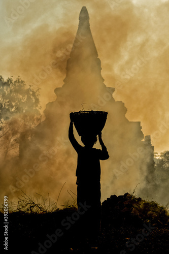 Bagan, Myanmar - 30 january 2019: lady burning scrub bushes around temples of Bagan. photo