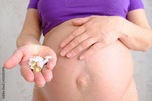 woman holding her belly. pills in the hand of a pregnant woman, with the other hand she shows rejection, health care