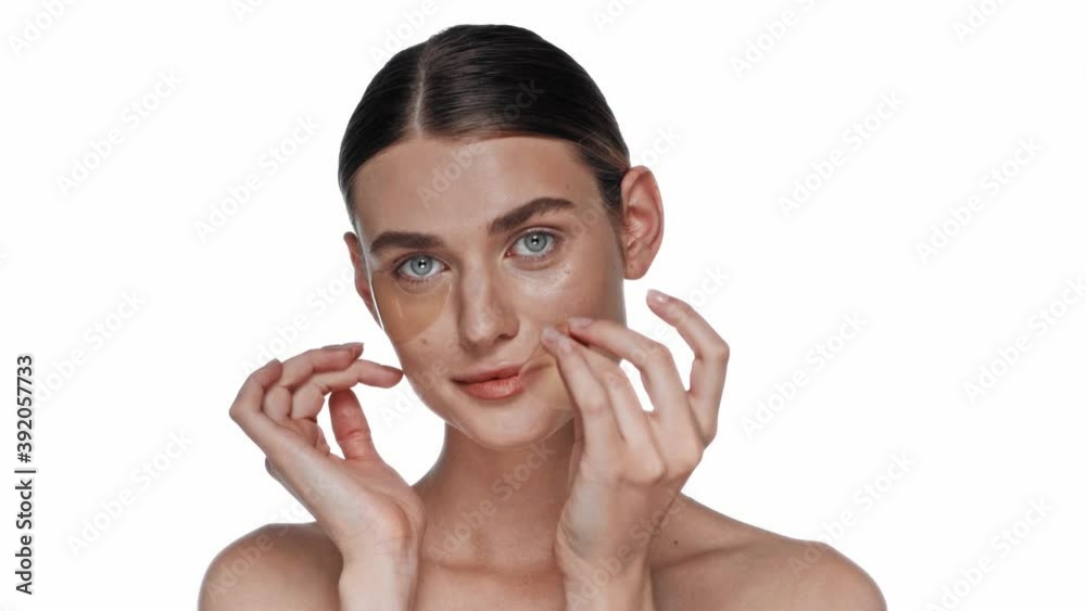 Smiling young adult woman removing eye patches isolated on white Smiling young adult woman removing eye patches isolated on white