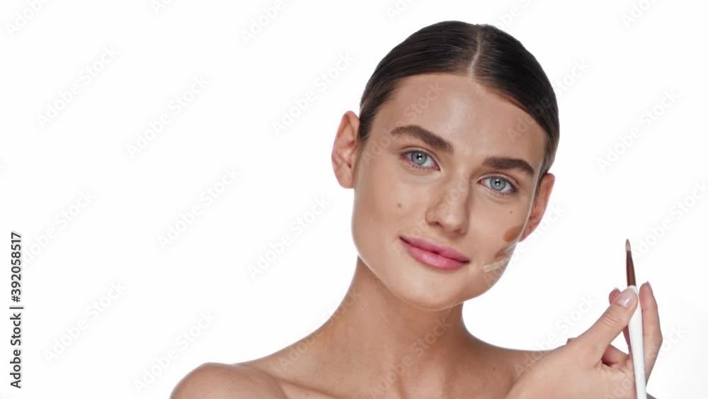 Young adult woman applying shades of concealer on cheek isolated on white Young adult woman applying shades of concealer on cheek isolated on white