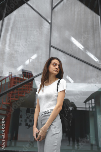 Young pretty woman stands on the background of a glass transparent building