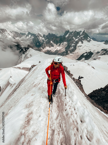 Young female climber on narrow snow ridge above glaciers Mt Blanc