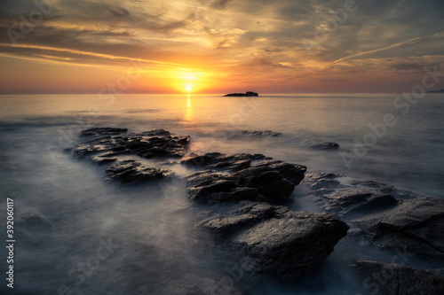 Beautiful sunset on the coast with the waves passing over the rocks photo