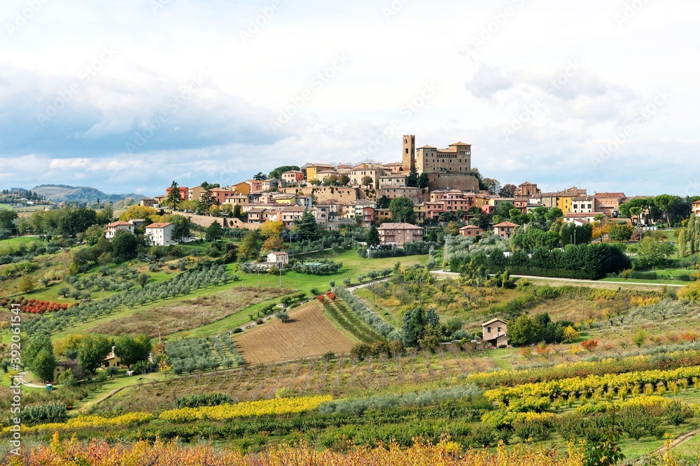 Beautiful landscape with small old town on the hill and surrounded by colorful autumn agriculture field against cloudy sky during autumn in Longiano,Province of Forli-Cesena,Italy