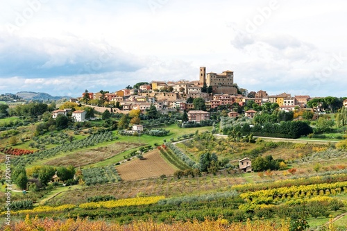 Beautiful landscape with small old town on the hill and surrounded by colorful autumn agriculture field against cloudy sky during autumn in Longiano,Province of Forli-Cesena,Italy photo