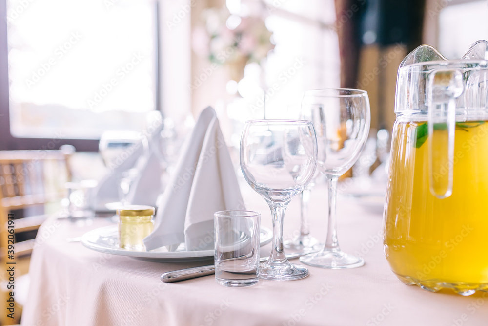 Glasses and plates on the table in the restaurant. Romantic luxury dining table with empty utensils Glasses and plates on the table in the restaurant. Romantic luxury dining table with empty utensils