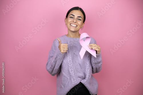 Obraz na płótnie Beautiful woman wearing a casual violet sweater over pink background holding bre