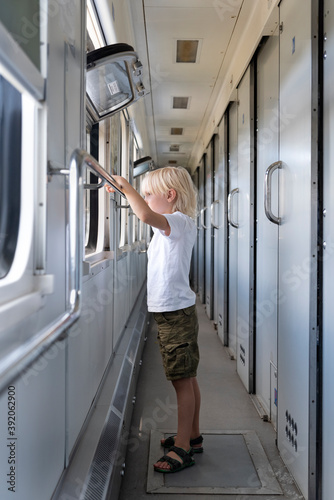 Sad boy with interest looks in the window of the train. Traveling with children