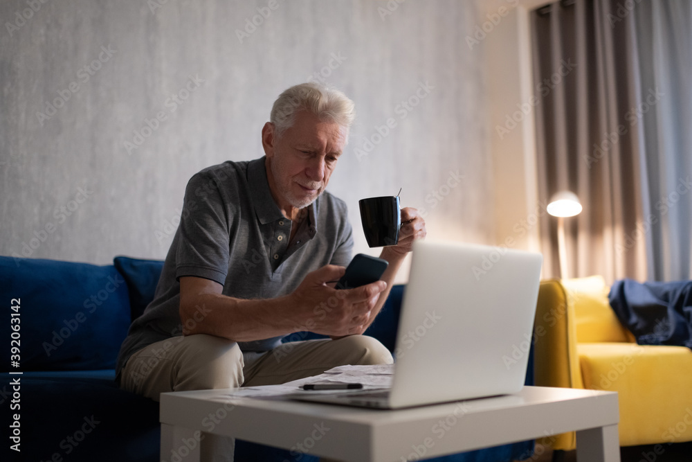 Aged man with cup using smartphone