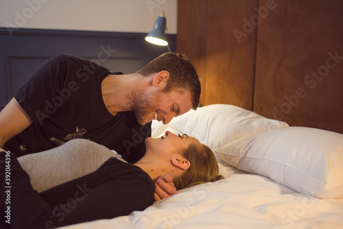 Optimistic couple cuddling on bed
