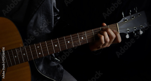 musician with a guitar on a black background in a leather jacket