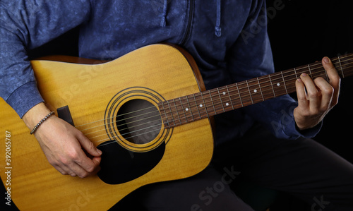 man playing acoustic guitar on a black background