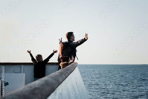 father and his children playing titanic feeling the breeze on a boat photo