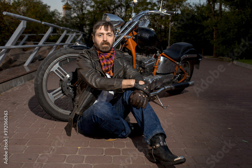 charismatic man sitting near his motorcycle