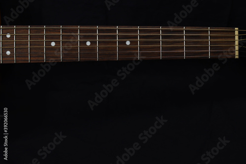 neck of the classic wooden acoustic guitar closeup, on a black background. Copy space for your text