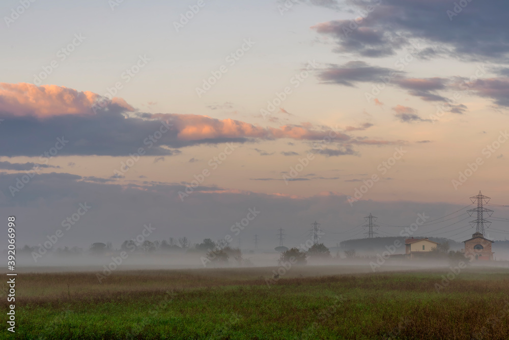 Fog envelops the Tuscan countryside near Pisa, Italy, just before sunset