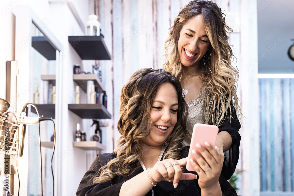 Woman with smartphone and hairdresser making hair styling at salon Woman with smartphone and hairdresser making hair styling at salon