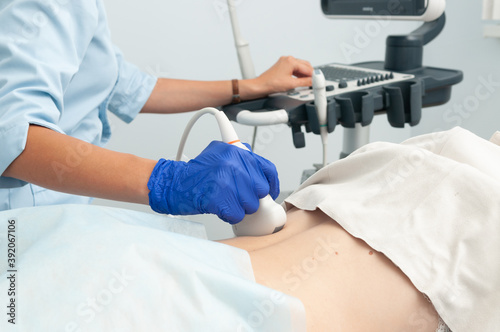 Ultrasound investigation of kidneys. The doctor runs the ultrasound sensor on the girl's back.