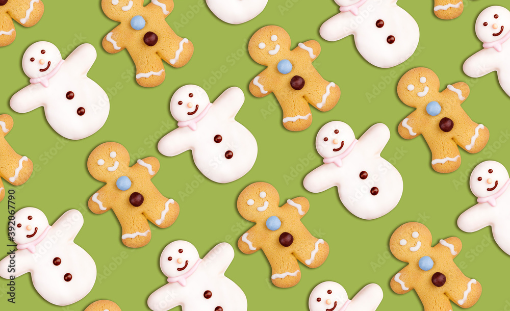 Obraz premium Christmas cookies pattern in the shape of a snowman and a gingerbread man decorated with icing sugar and fondant on a green background