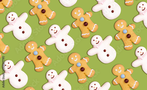 Christmas cookies pattern in the shape of a snowman and a gingerbread man decorated with icing sugar and fondant on a green background