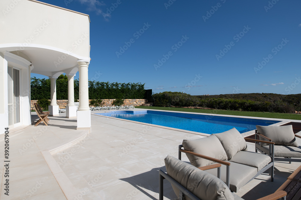 Fototapeta premium Large swimming pool in the garden of a luxury villa on the algarve with ceramic tiled surround and seating area