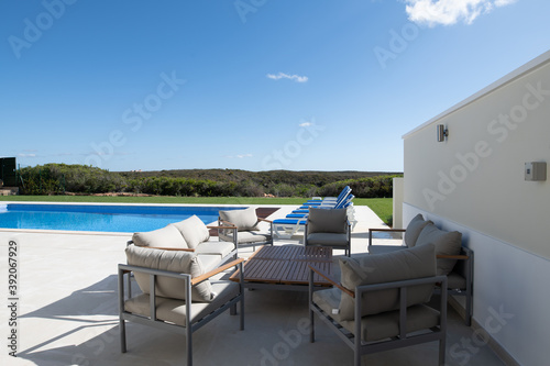 patio seating area in the garden of a luxury holiday villa with swimming pool in the background