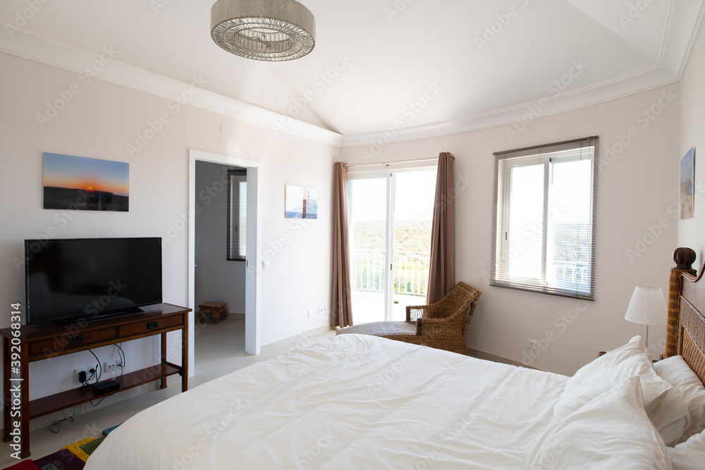 Master bedroom with wooden furniture, white bedding and sliding doors to terrace in a renovated holiday villa Master bedroom with wooden furniture, white bedding and sliding doors to terrace in a renovated holiday villa