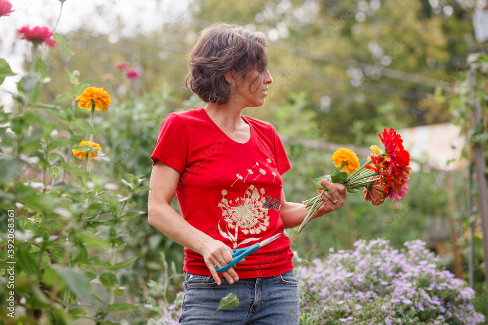 A woman stands with a bouquet of wildflowers in a beautiful garden A woman stands with a bouquet of wildflowers in a beautiful garden