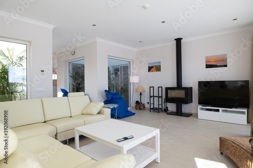 Modern, clean living room of luxury family house with large l-shape leather sofa and tiled floors
