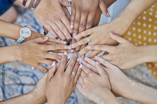 Detail of a group of multiracial friends joining hands in a park