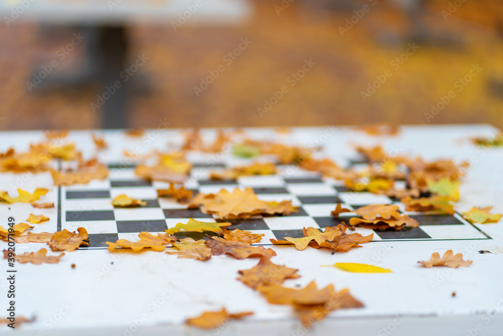 Chess tables covered with yellow leaves in an autumn park Chess tables covered with yellow leaves in an autumn park