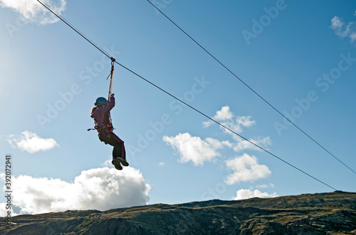 girl going down on a zip line at high rope access course in Iceland photo