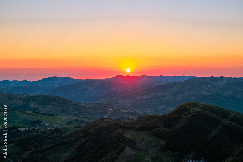Red sun rising over the colorful sky and mountains landscape. Sunrise in mountains, Natural background. Italian Apennine	
