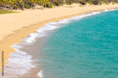Fototapeta Naklejka Na Ścianę i Meble -  Beautiful empty sandy beach and soft turquoise sea wave and white foam on paradise tropical island
