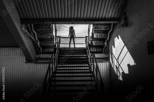 Sporty woman relaxing on the stairs of stadium in black and white