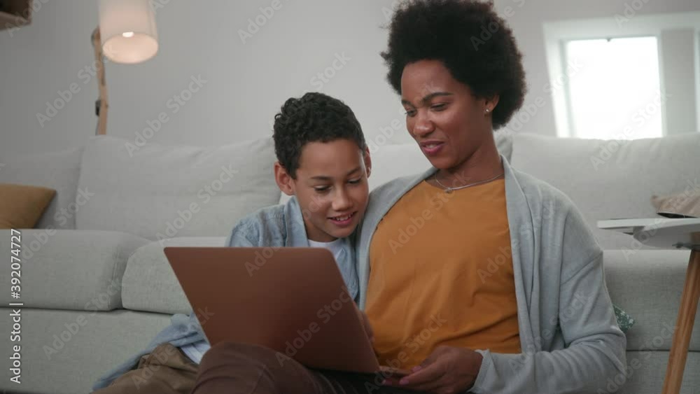 Afro mother and son sitting on floor and using digital tablet Afro mother and son sitting on floor and using digital tablet
