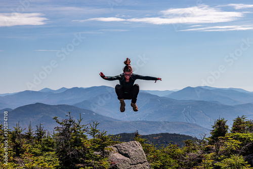Young athletic woman jumping at top of mountain peak. photo