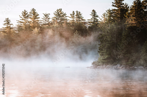 Early morning mist rises off calm waters of Bald Mountain Pond, Maine