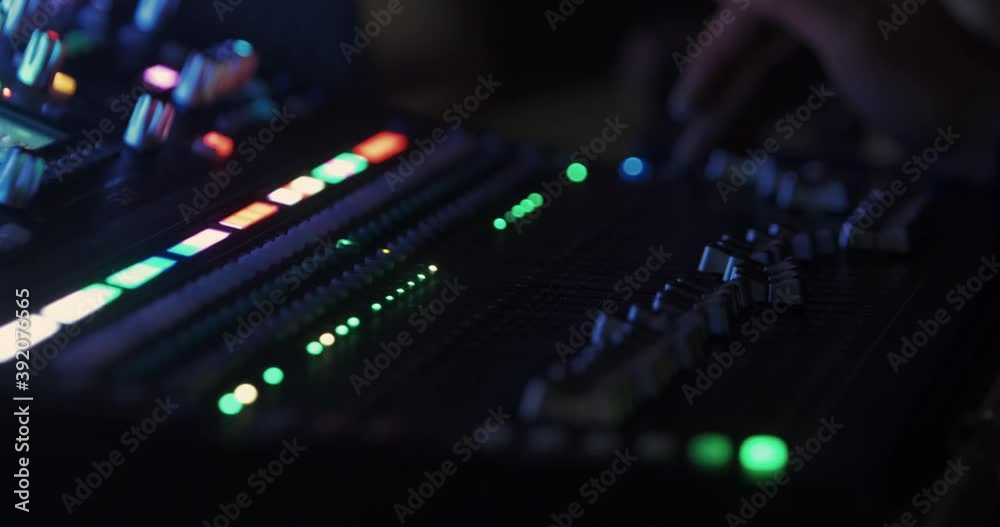 The sound engineer switches the sound modes on the music console, where the volume controls move and the LED lights flash. 