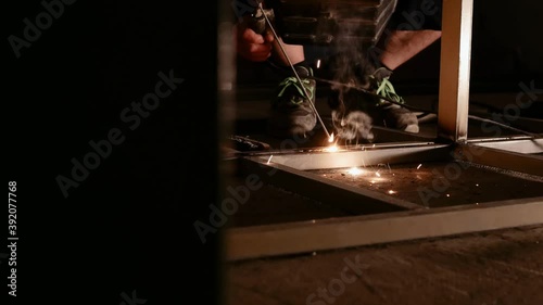 Man with mask soldering a metal strcture in workshop. photo