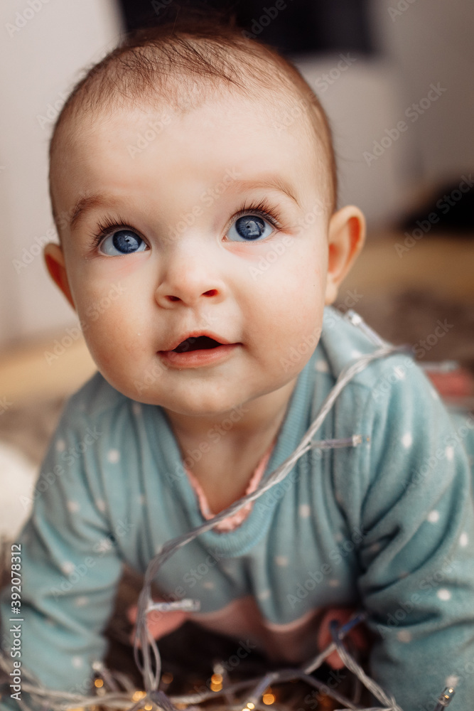 Cute toddler crawl on fours near light garland on blanket, beautiful baby girl excited about first Christmas, new year celebration with little child, winter holidays concept Cute toddler crawl on fours near light garland on blanket, beautiful baby girl excited about first Christmas, new year celebration with little child, winter holidays concept