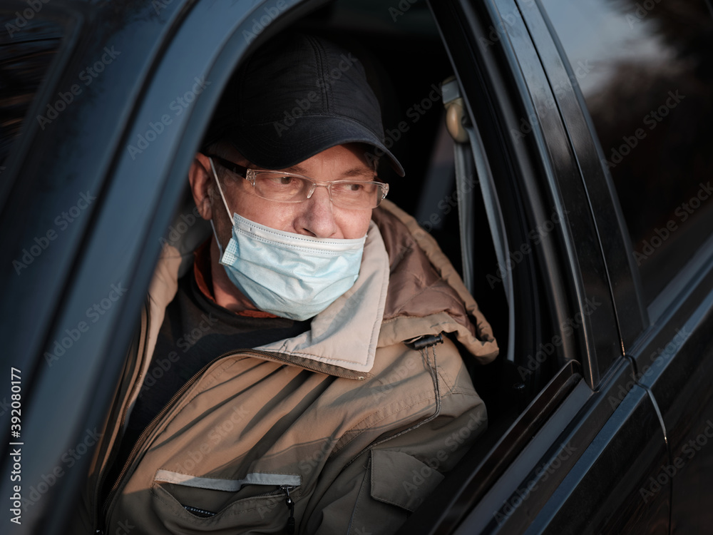 A man in a car with an incorrectly worn medical mask A man in a car with an incorrectly worn medical mask