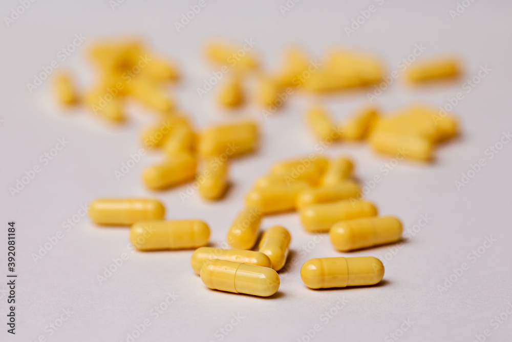 Yellow capsules with medicine are scattered on a white background. Yellow capsules with medicine are scattered on a white background.