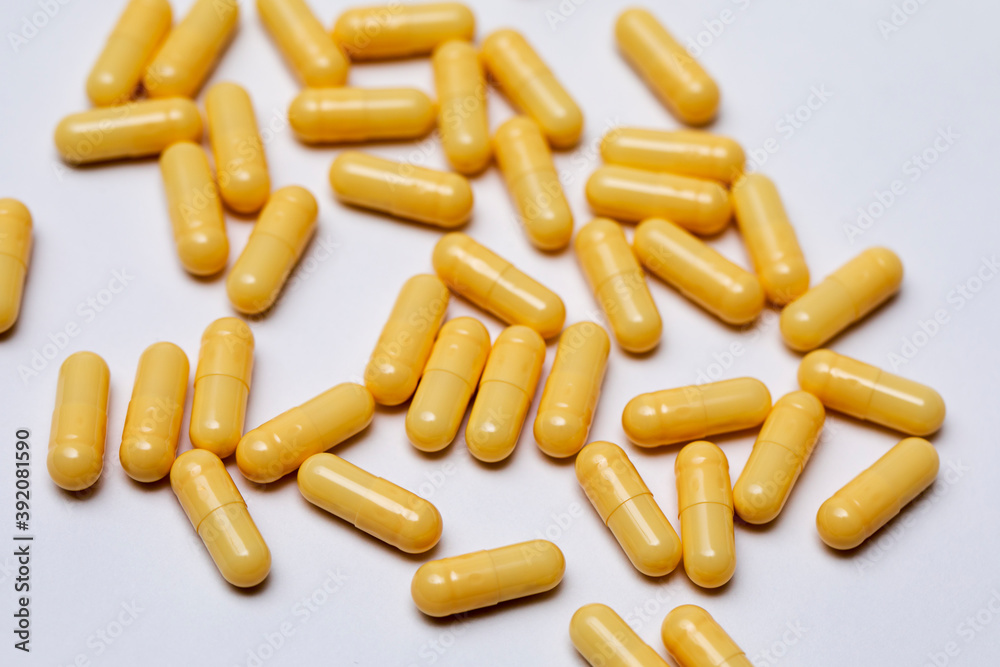 Yellow capsules with medicine are scattered on a white background. Yellow capsules with medicine are scattered on a white background.