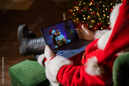 Happy mom and son talking to santa claus by video chat on a laptop. Woman and boy remotely wishes Merry Christmas © Михаил Решетников