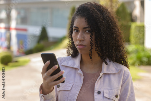 Black woman on urban background texting on cellphone