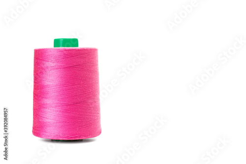 Carrete de hilo rosa fucsia para la industria textil sobre un fondo blanco liso y aislado. Vista de frente. Copy space