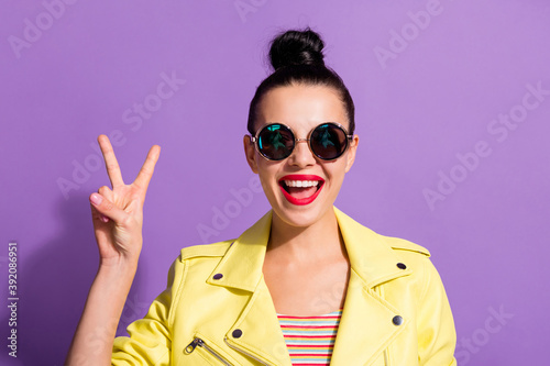 Photo of young happy positive good mood beautiful woman girl female showing v-sign isolated on purple color background © deagreez