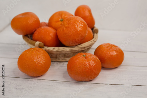 Mandarins in a basket on a white wooden background.