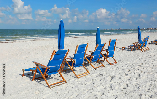Fototapeta Naklejka Na Ścianę i Meble -  Blue beach chairs and umbrellas facing the Gulf of Mexico on a beautiful day in Fort Myers Beach, Florida, USA.